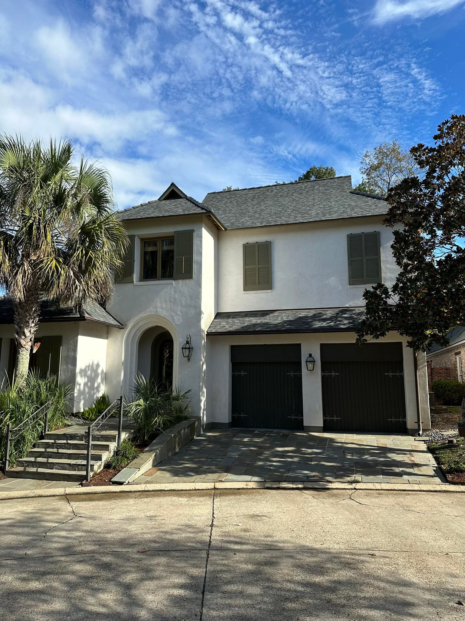 A large white house with a gray roof and two garages.