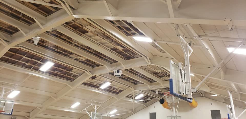 A basketball hoop is hanging from the ceiling of a gym.