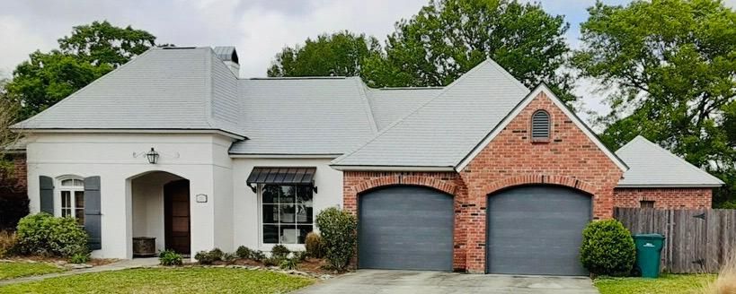 A brick house with two garage doors and a white roof.