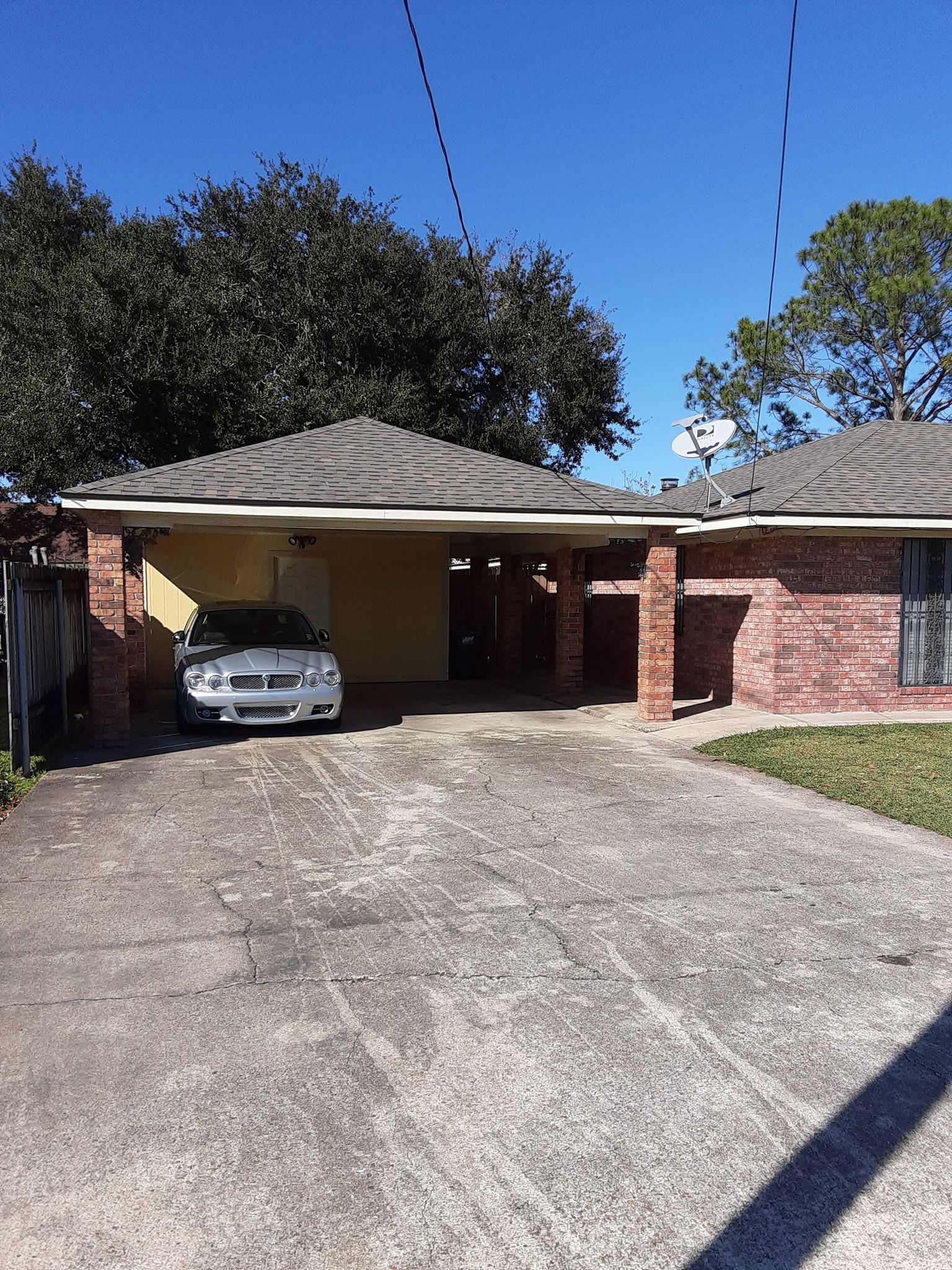 A white car is parked in front of a brick house.