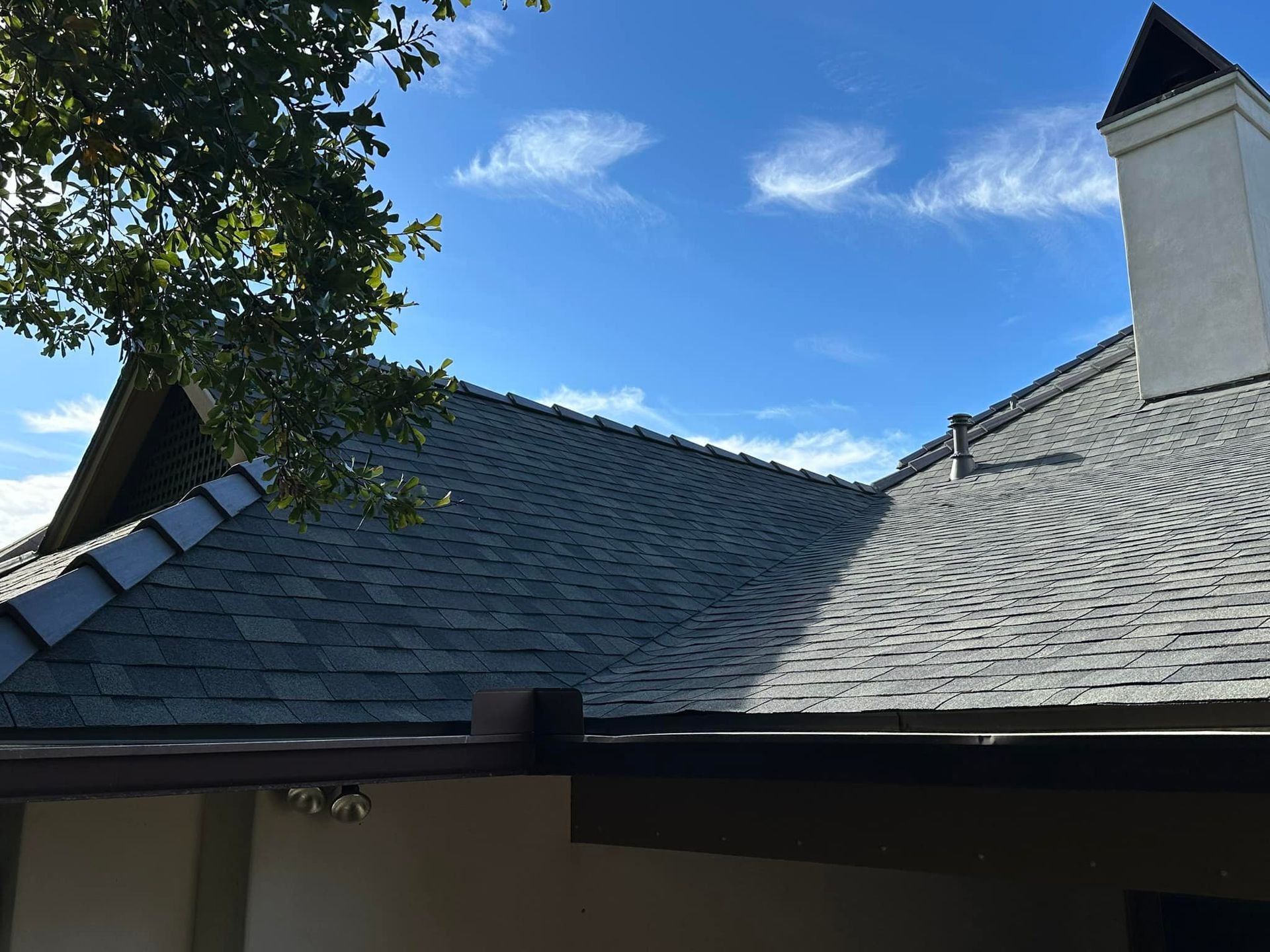 A roof with a chimney on top of it and a blue sky in the background