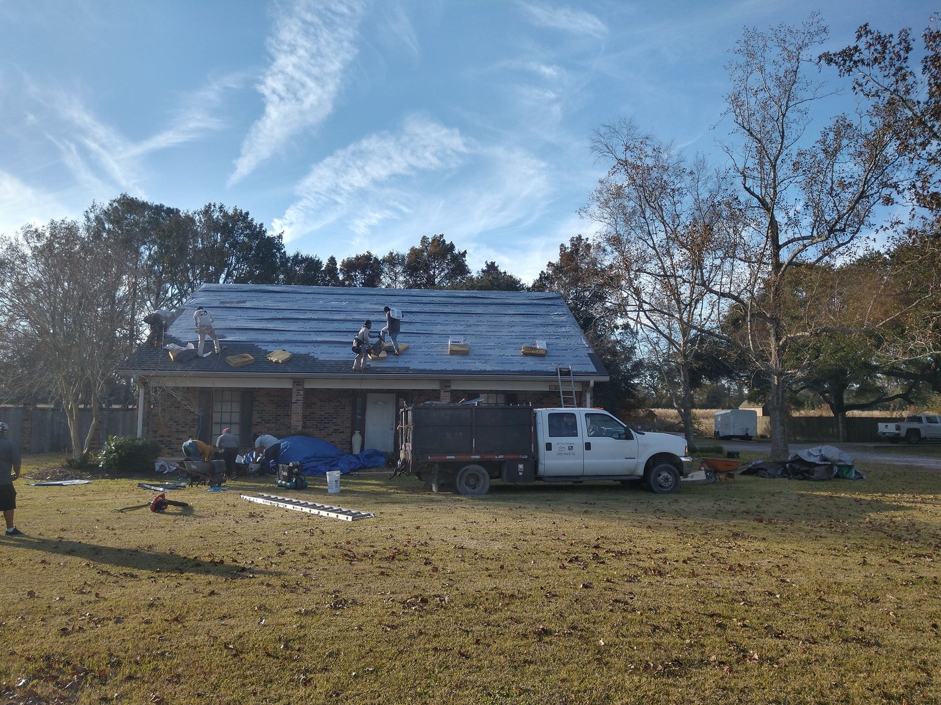 A white truck is parked in front of a house under construction.