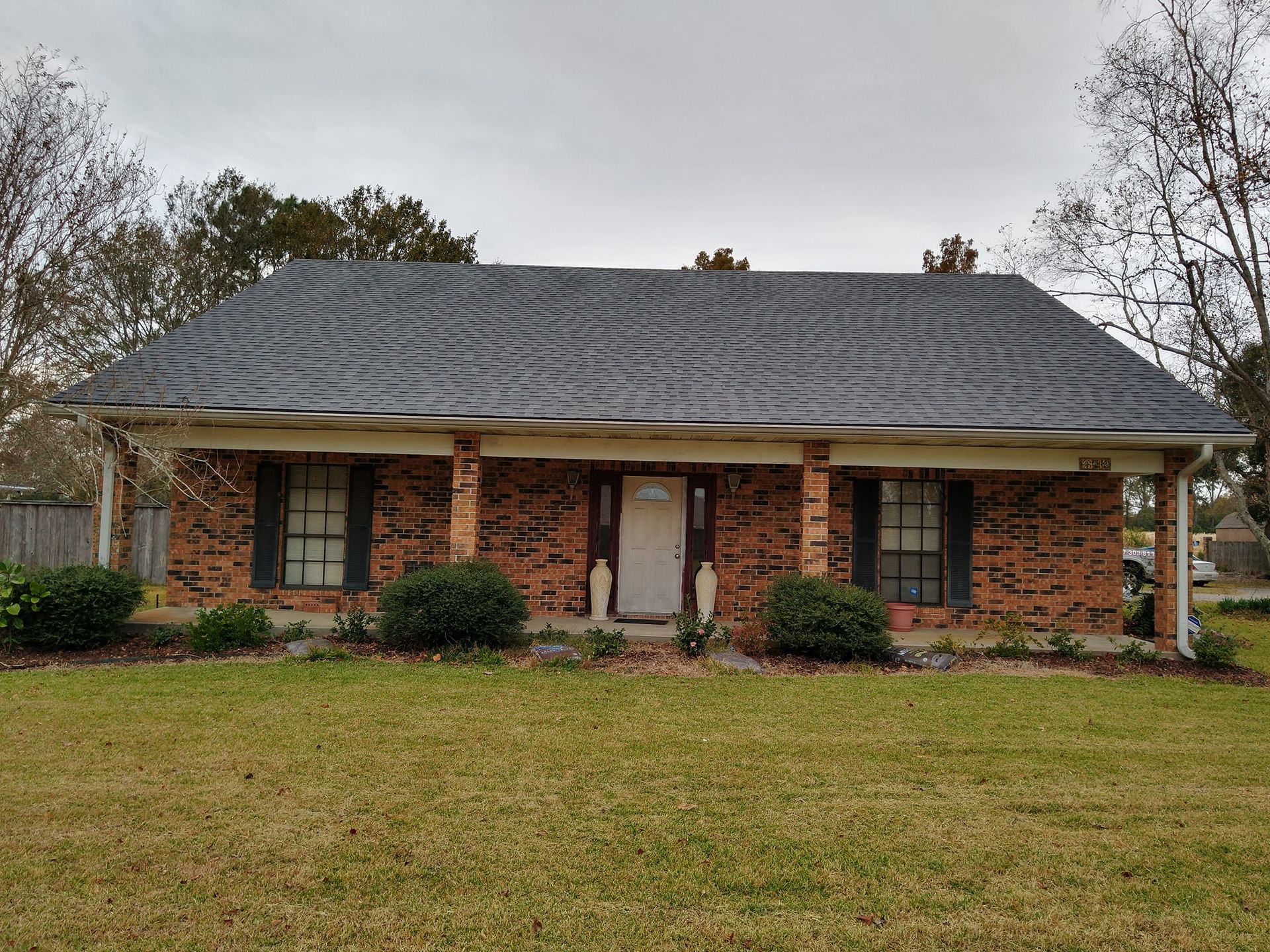 A brick house with a gray roof and black shutters