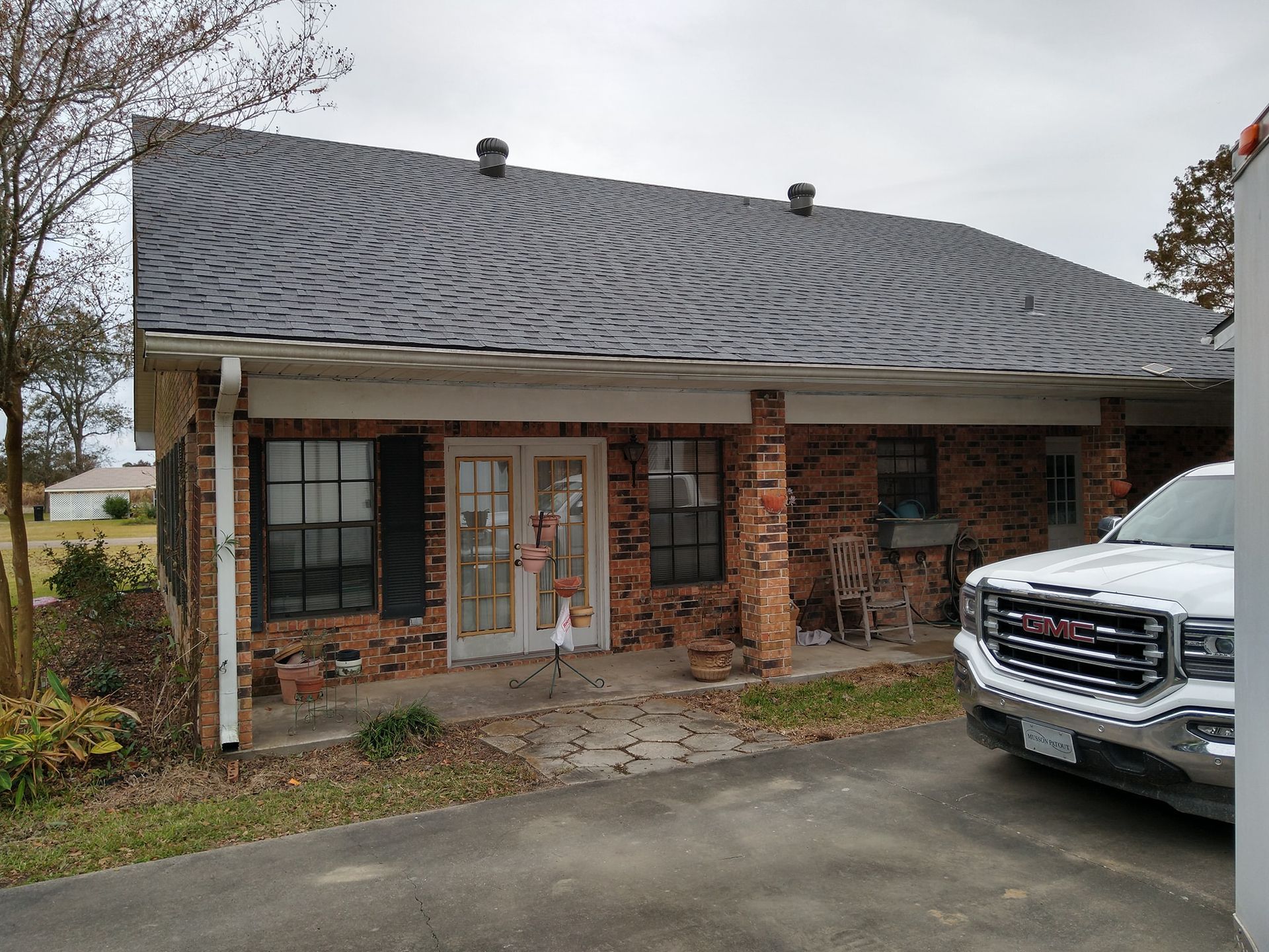 A white truck is parked in front of a brick house.
