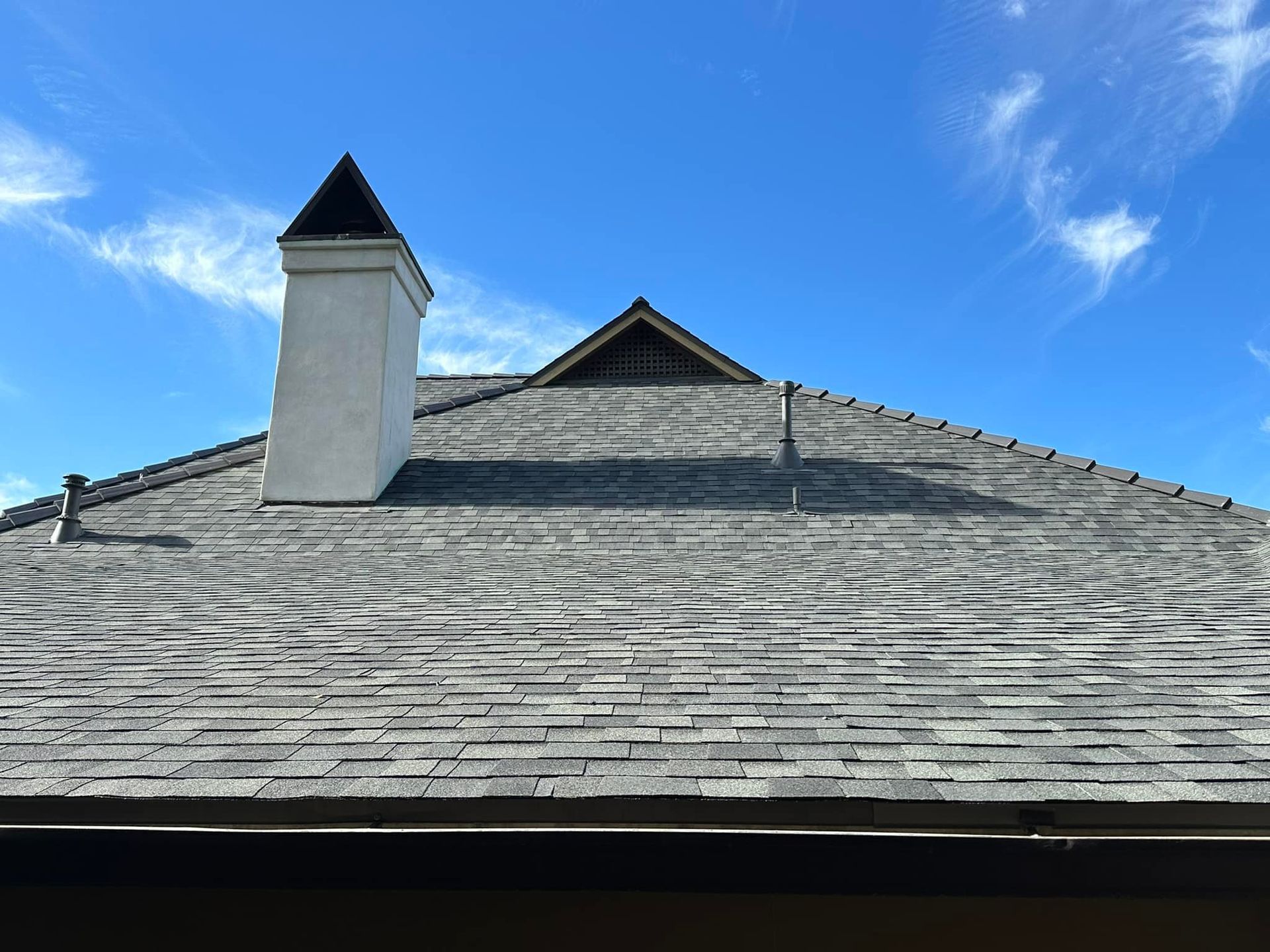 A roof with a chimney on it and a blue sky in the background