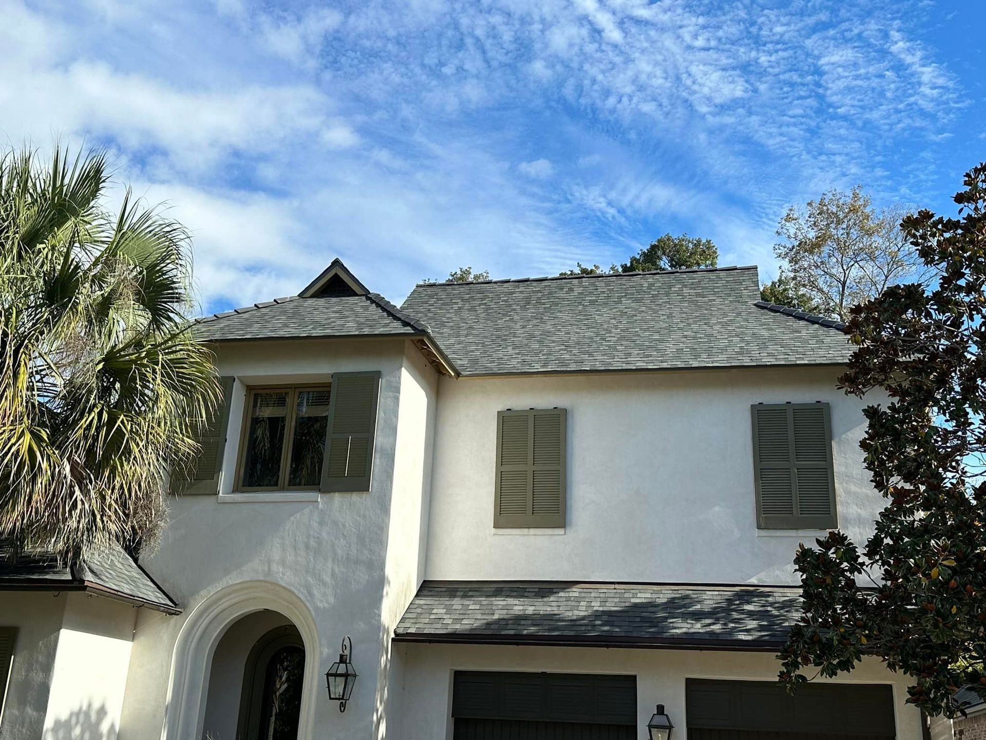 A white house with a gray roof and green shutters