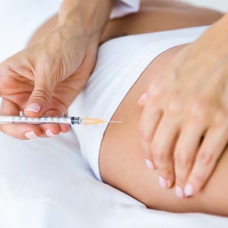 A person receiving an injection in the thigh. A hand holds a syringe to administer a shot.