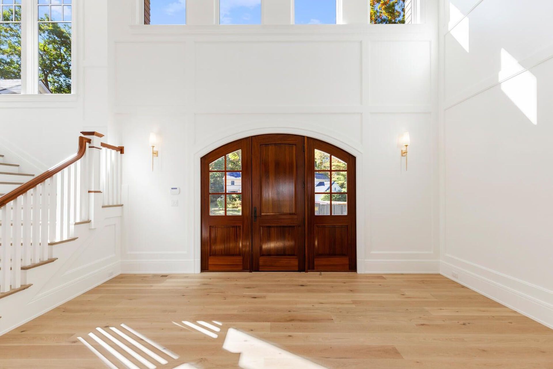 A large empty room with a wooden door and stairs.
