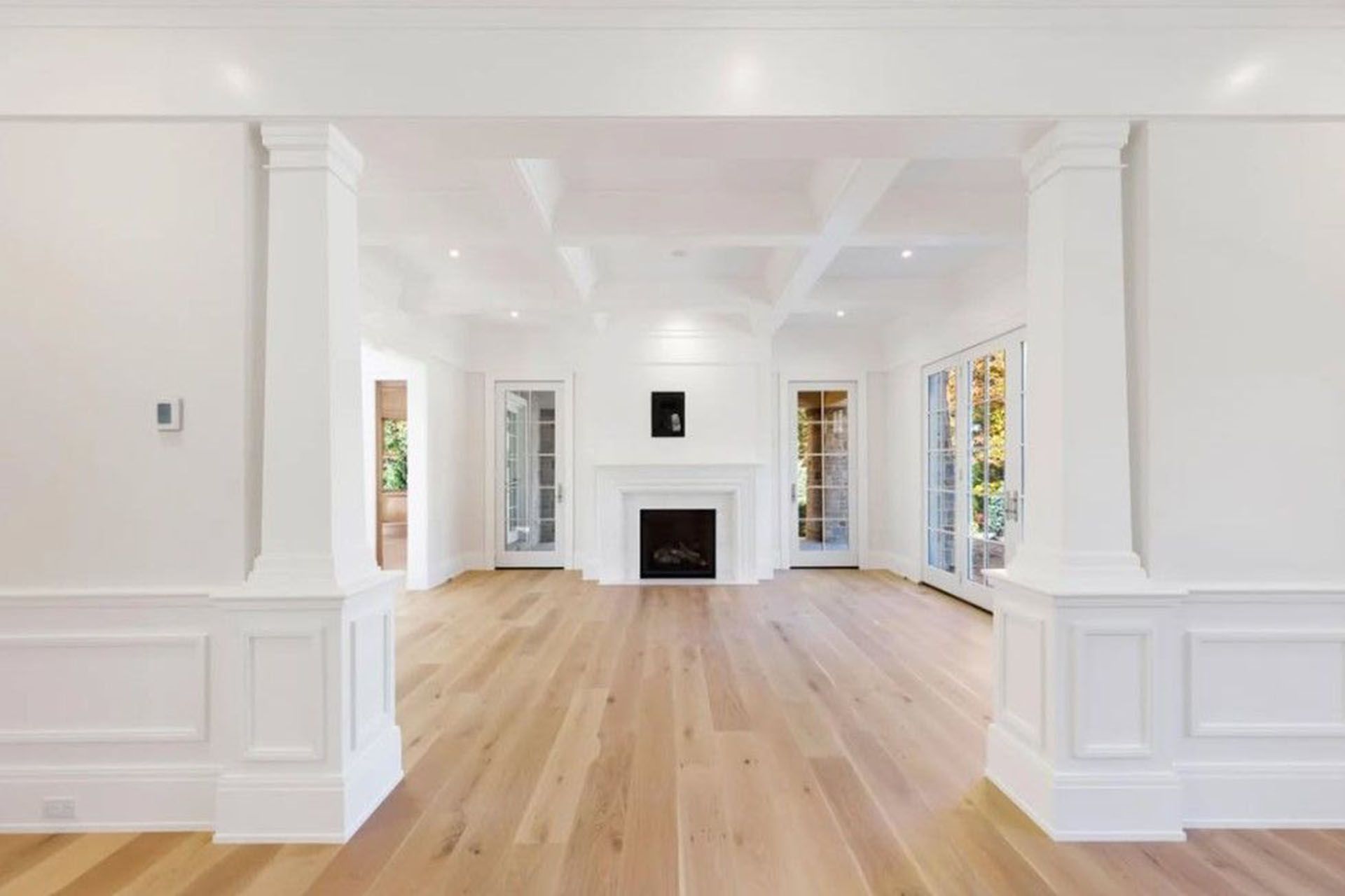 An empty living room with hardwood floors and a fireplace.