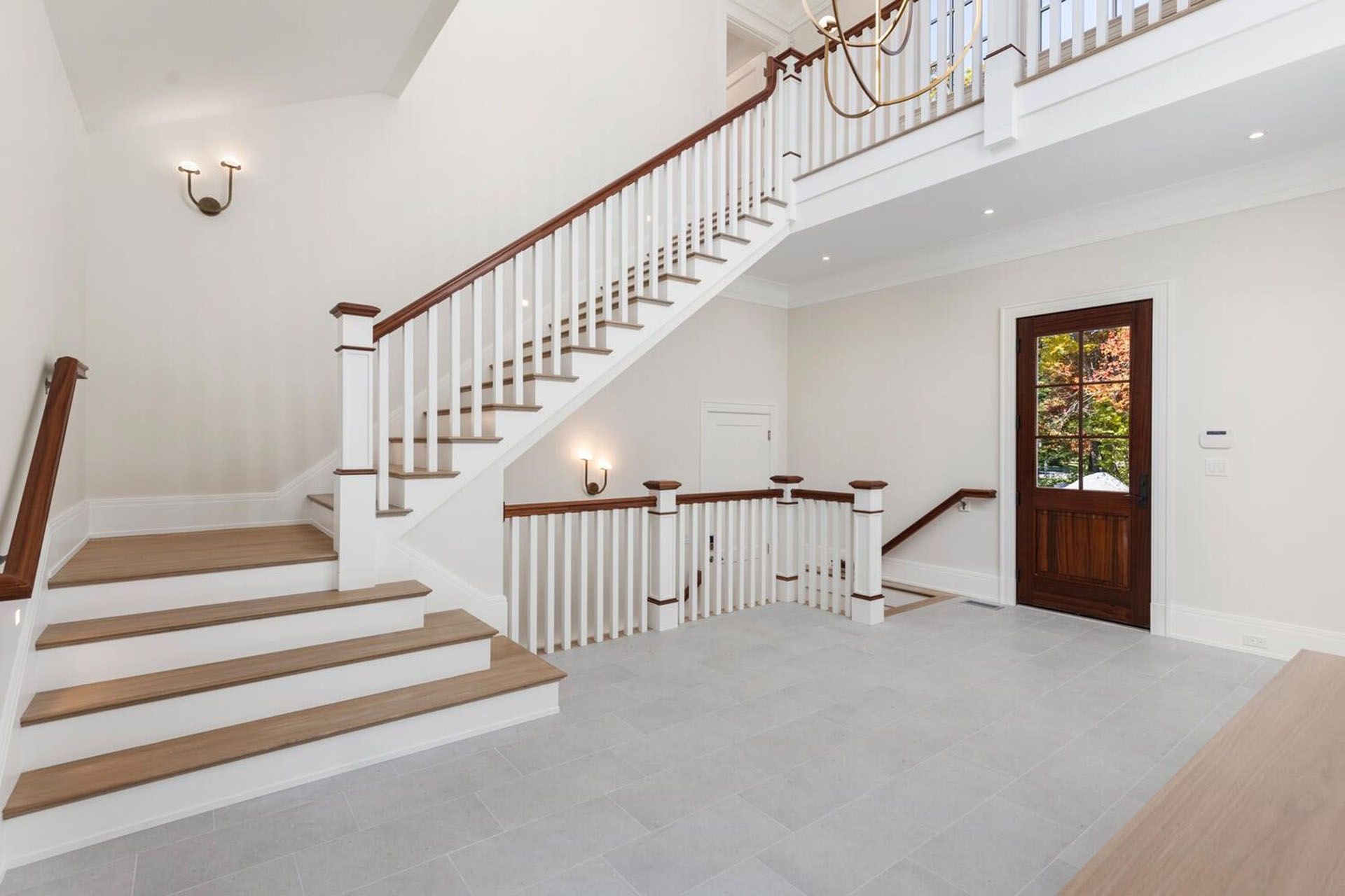 An empty hallway with a staircase and a door.