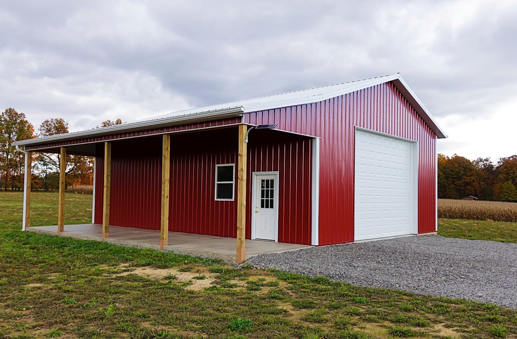 A red barn with a white garage door is sitting in the middle of a grassy field.