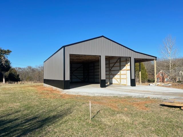 A large metal building is sitting in the middle of a grassy field.