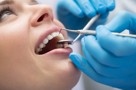 A woman is getting her teeth examined by a dentist.