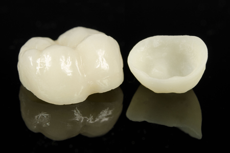 A dental crown and a dental crown on a black surface.