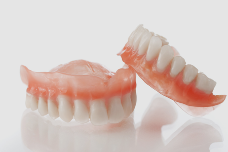 A pair of dentures sitting on top of each other on a white surface.