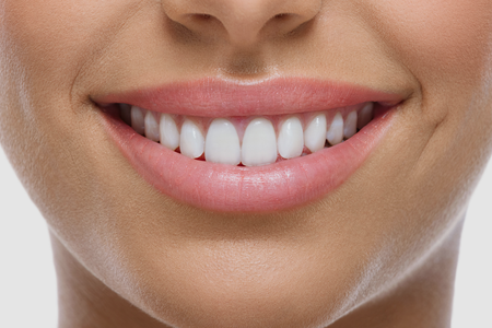 A close up of a woman 's smile with white teeth and pink lips.