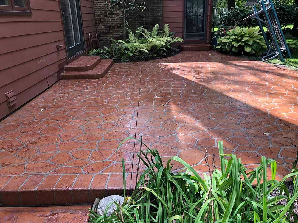 A patio with a stenciled pattern on it is in front of a house.