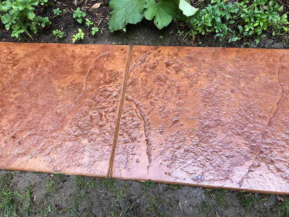 A close up of a concrete walkway next to a garden.