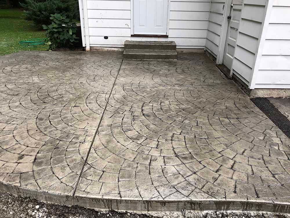 A concrete patio in front of a white house.