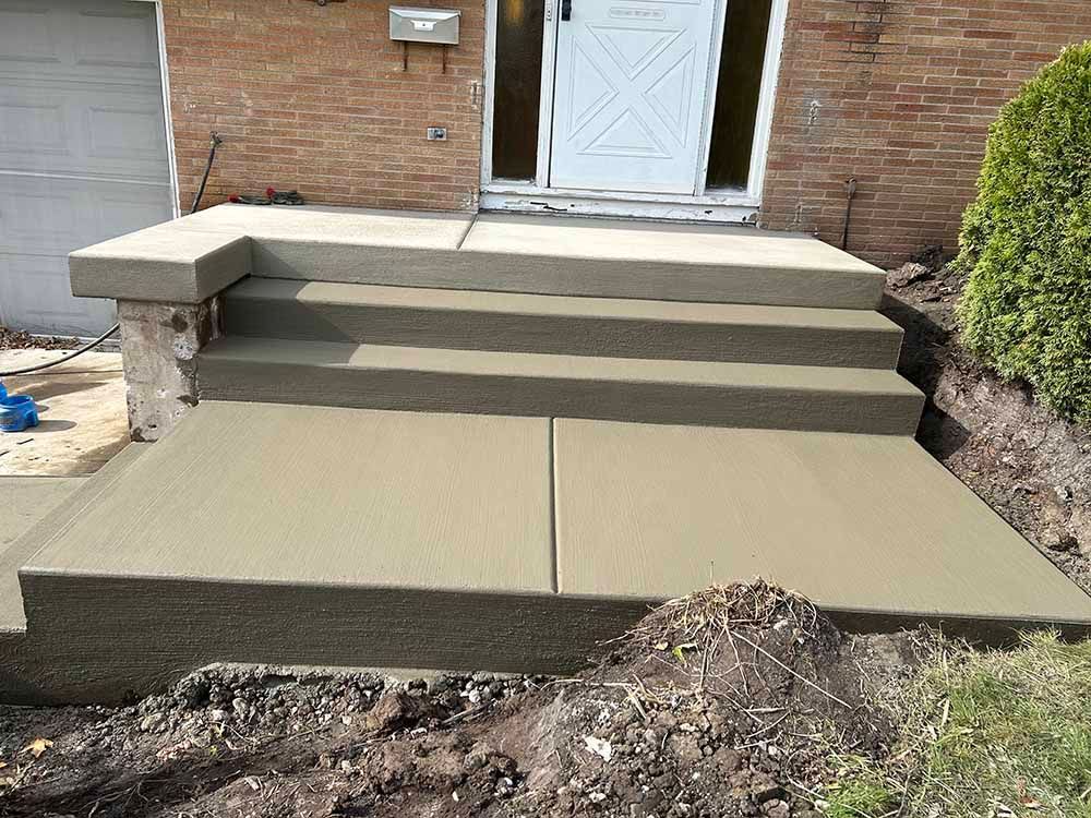 A concrete staircase is being built in front of a brick house.