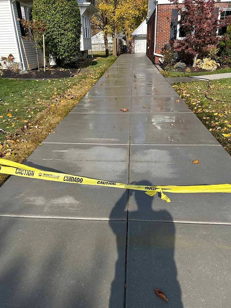 A shadow of a person is cast on a concrete sidewalk.