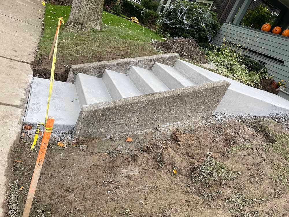 A set of concrete stairs being built in front of a house.