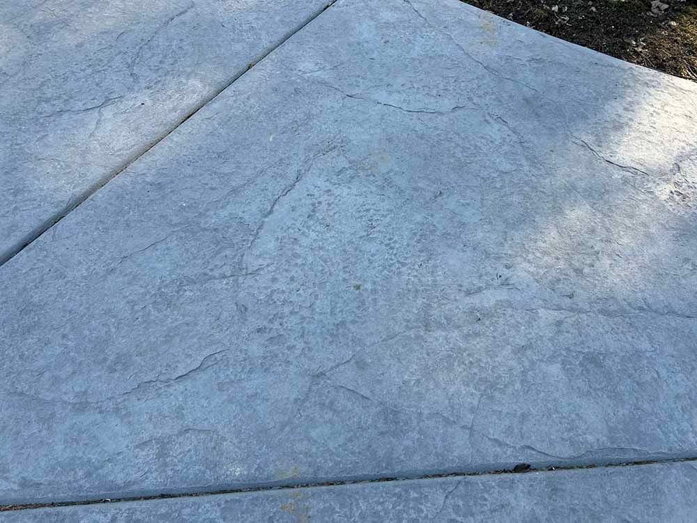 A close up of a concrete sidewalk with a marble texture.