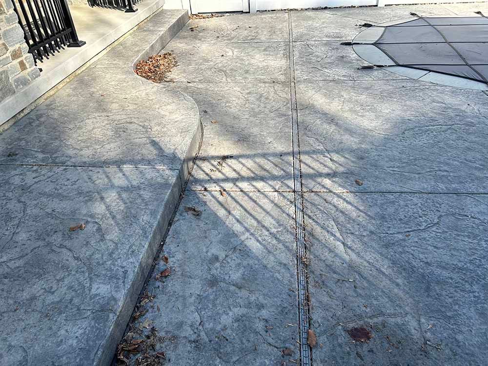 A concrete sidewalk with a shadow of a tree on it.