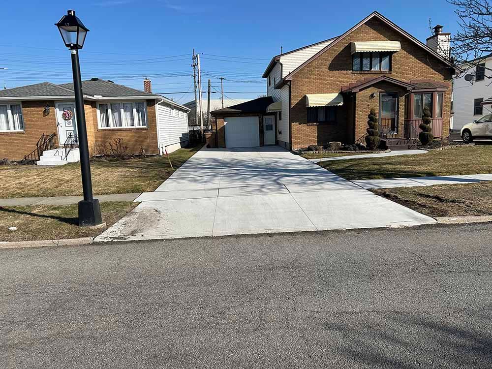 A driveway leading to a brick house with a car parked in front of it.