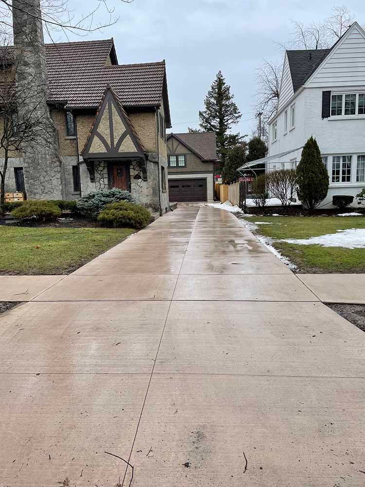 A concrete driveway leading to a house in a residential neighborhood.