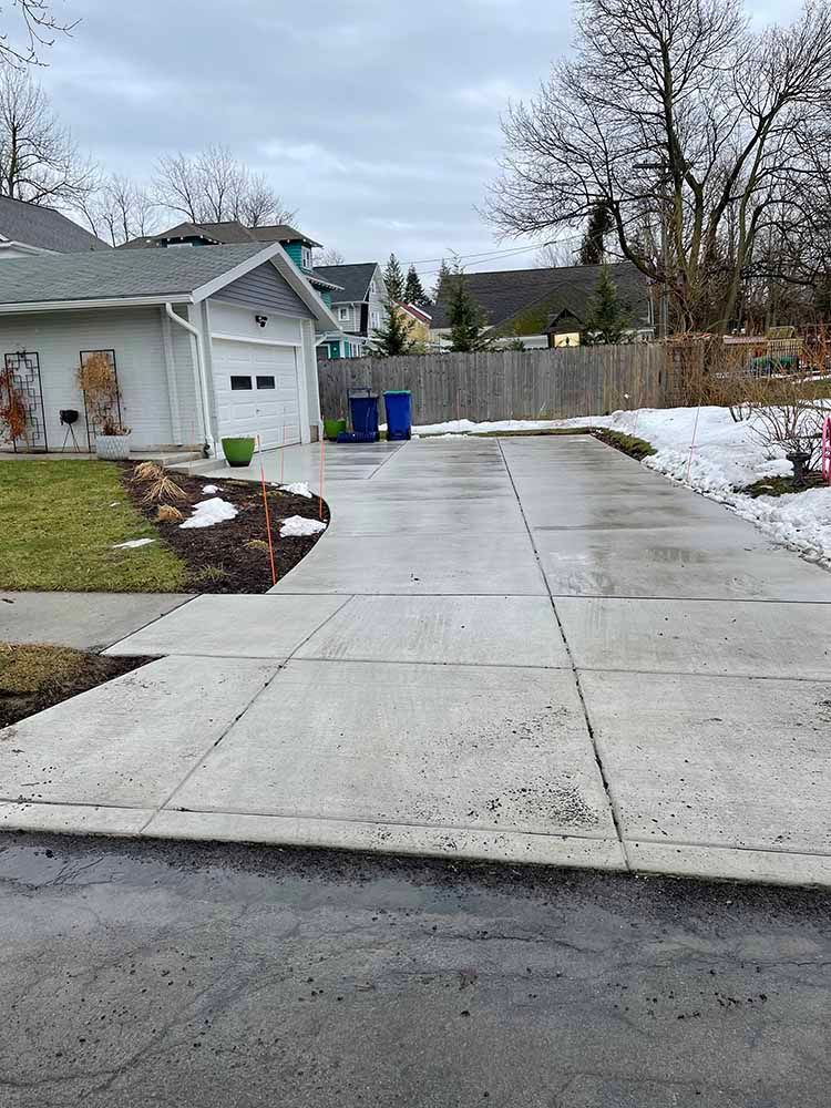 There is a concrete driveway leading to a house.