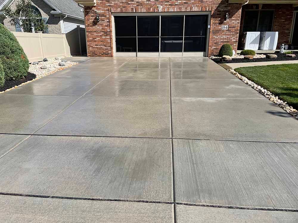 A concrete driveway in front of a brick house.