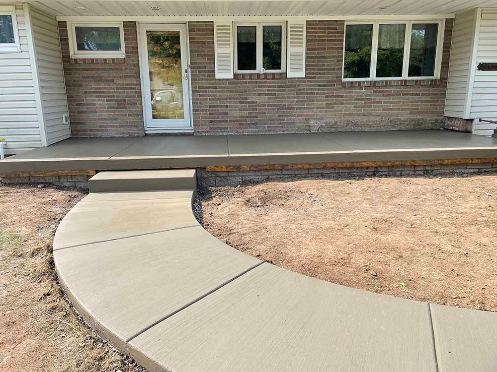 A brick house with a concrete walkway leading to the front door.