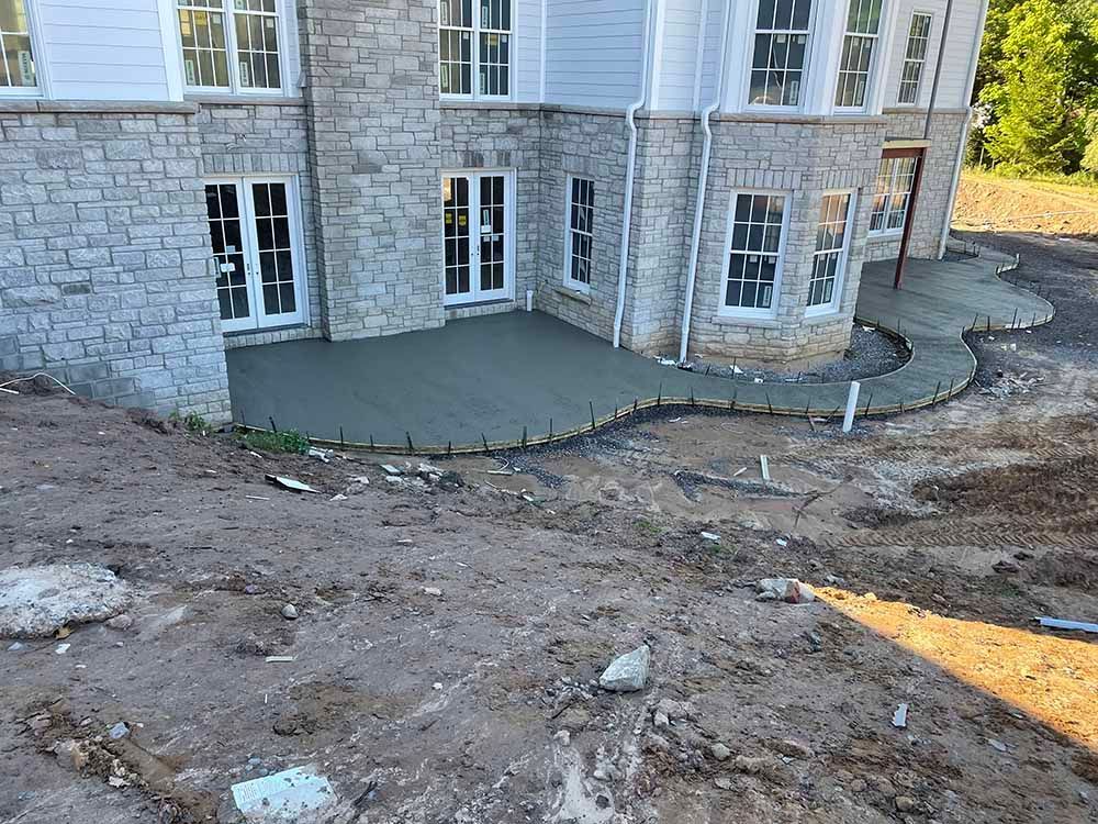 A large brick house with a concrete patio in front of it.