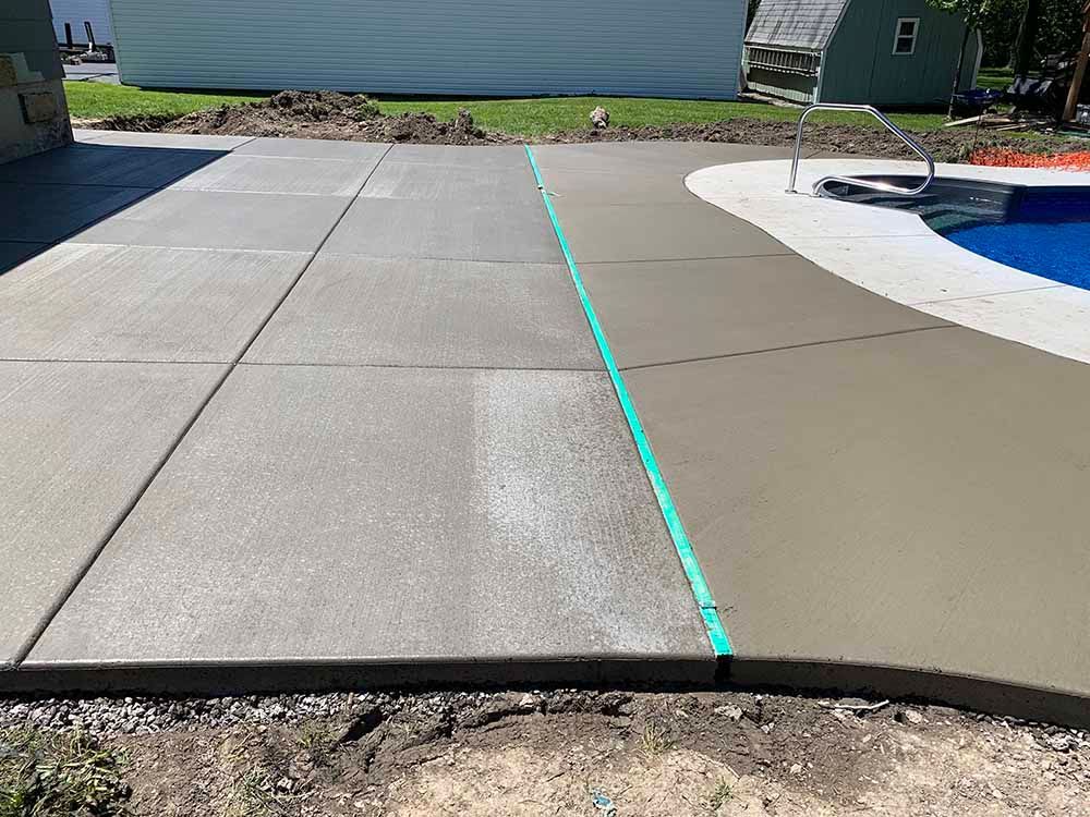 A concrete driveway is being built next to a swimming pool.