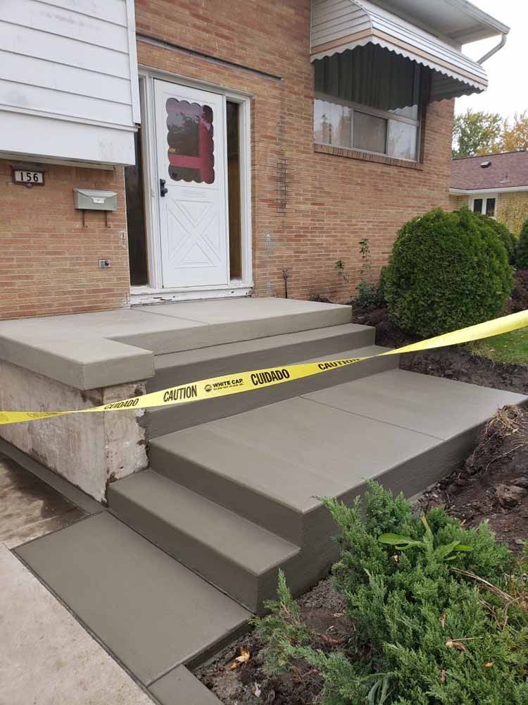A brick house with a concrete porch and steps being built.