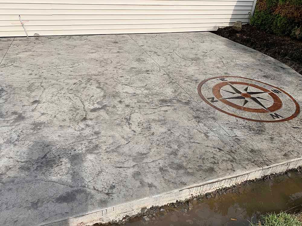 A concrete driveway with a compass design on it.