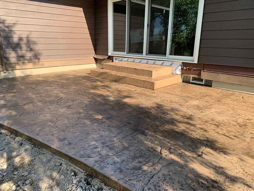 A concrete patio with steps leading to a house.
