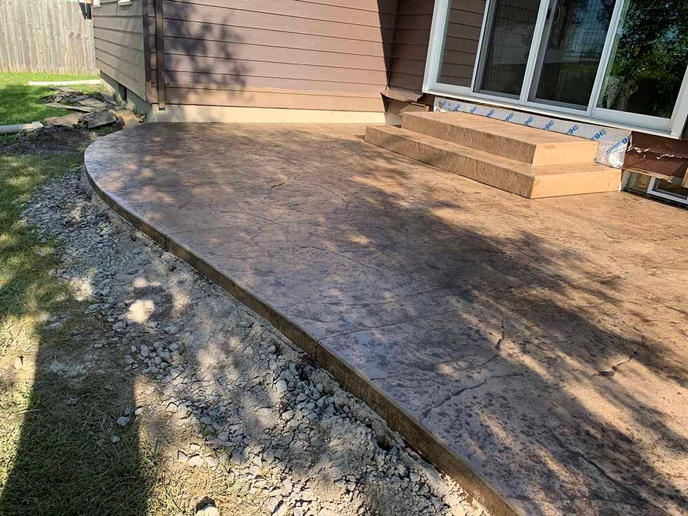 A concrete patio with steps leading to a house.