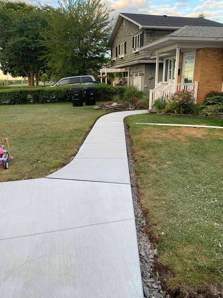 There is a concrete walkway leading to a house.