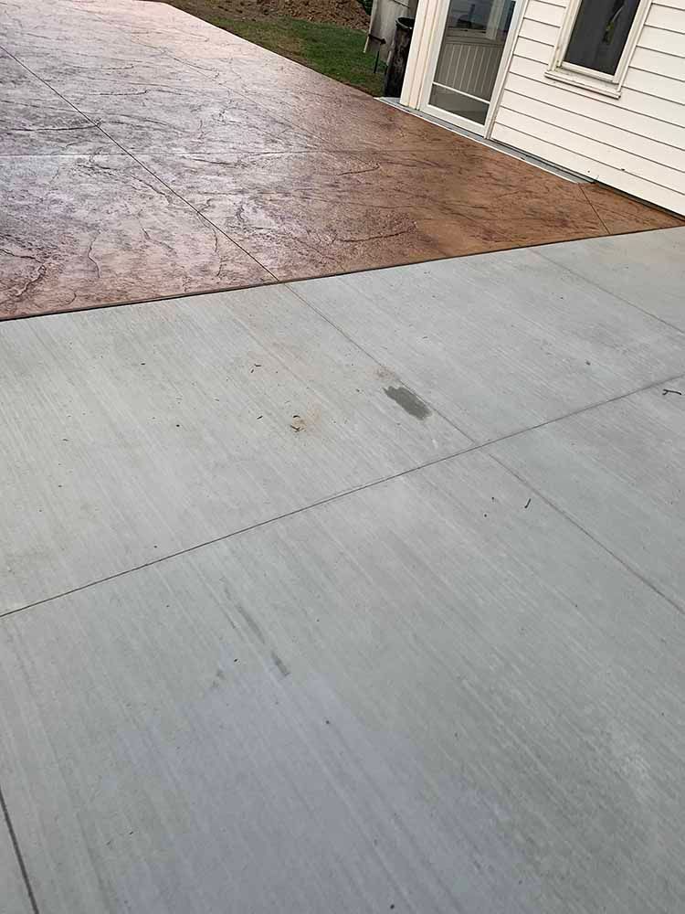 A concrete driveway with a stamped concrete driveway in front of a house.