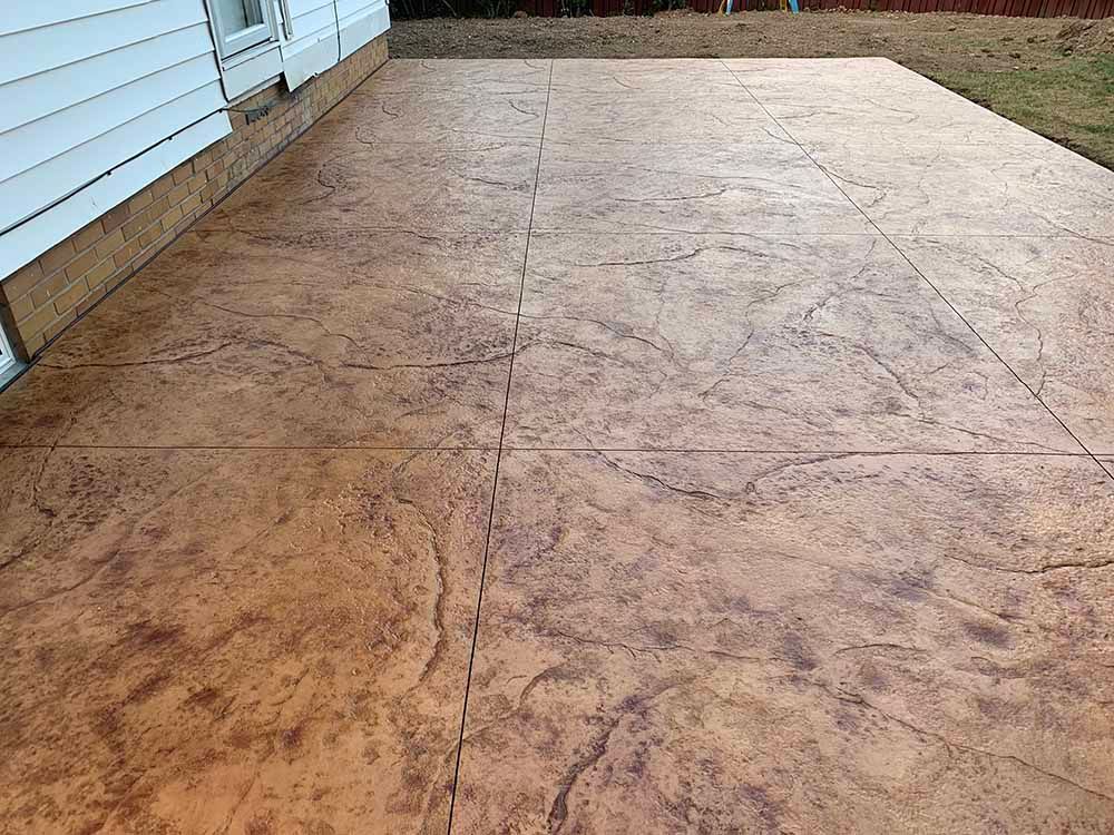 A patio with a concrete floor and a white house in the background.