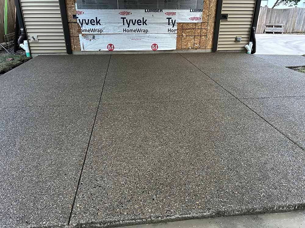 A concrete driveway with a garage door in the background.