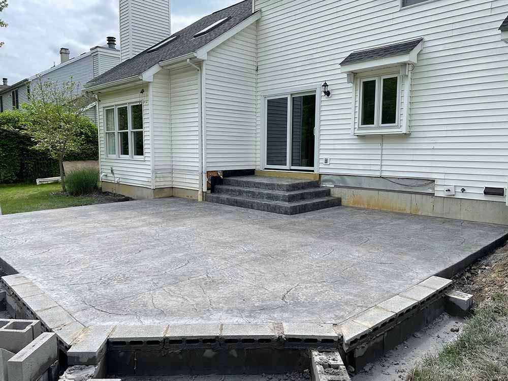 A white house with a concrete patio in front of it.