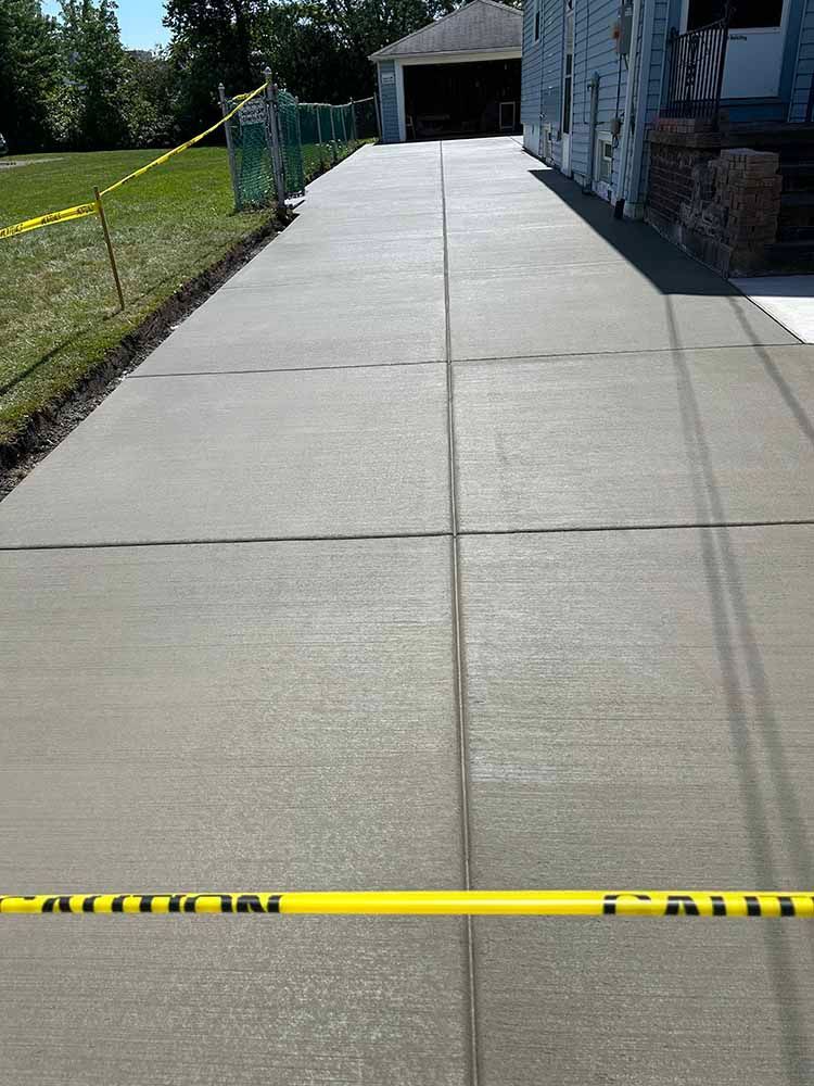 A concrete driveway with a yellow caution tape on it