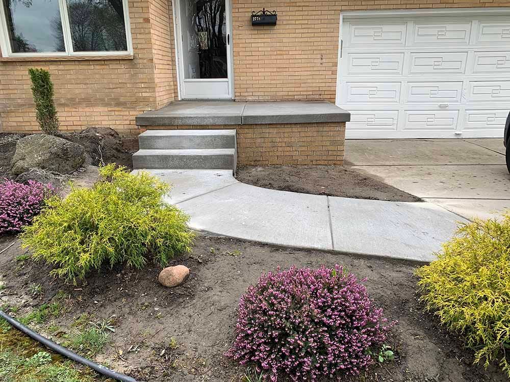 A brick house with a concrete walkway leading to the front door.
