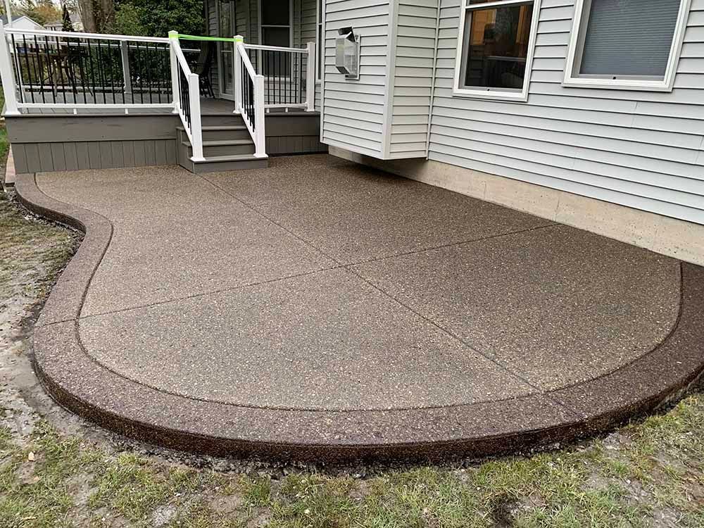 A patio with a deck and stairs in front of a house.