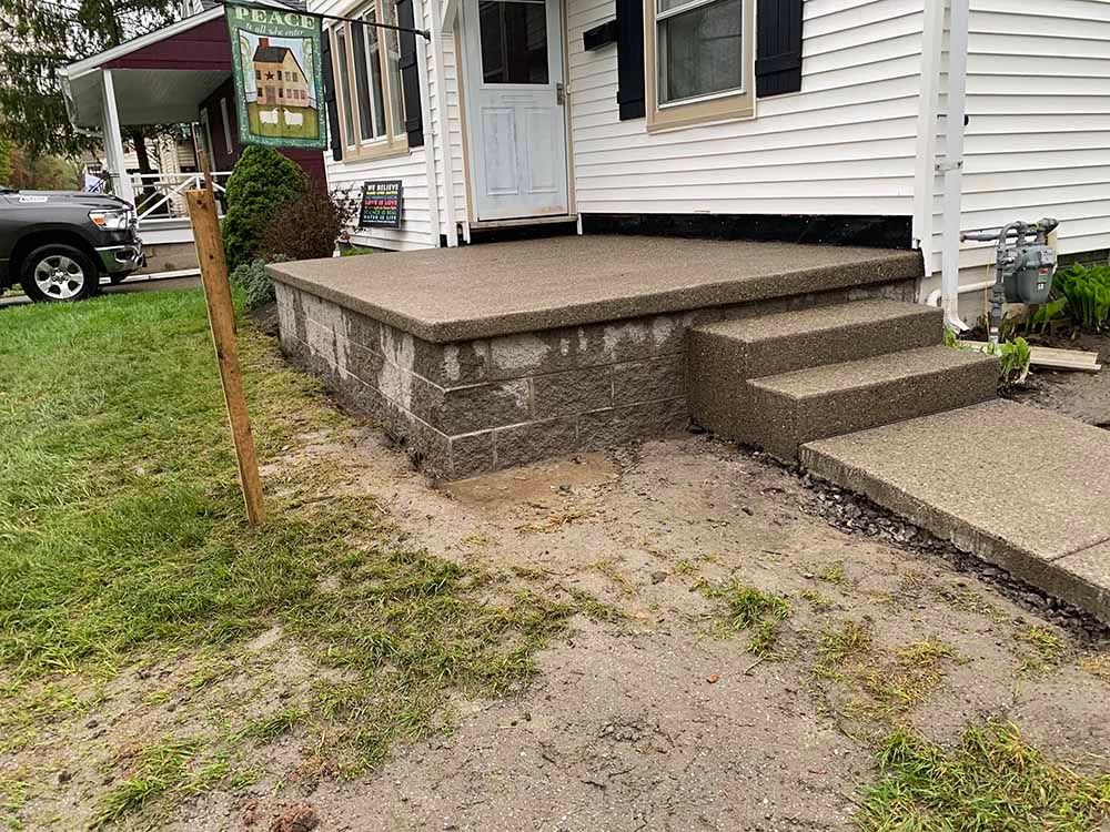 A white house with a concrete porch and steps.