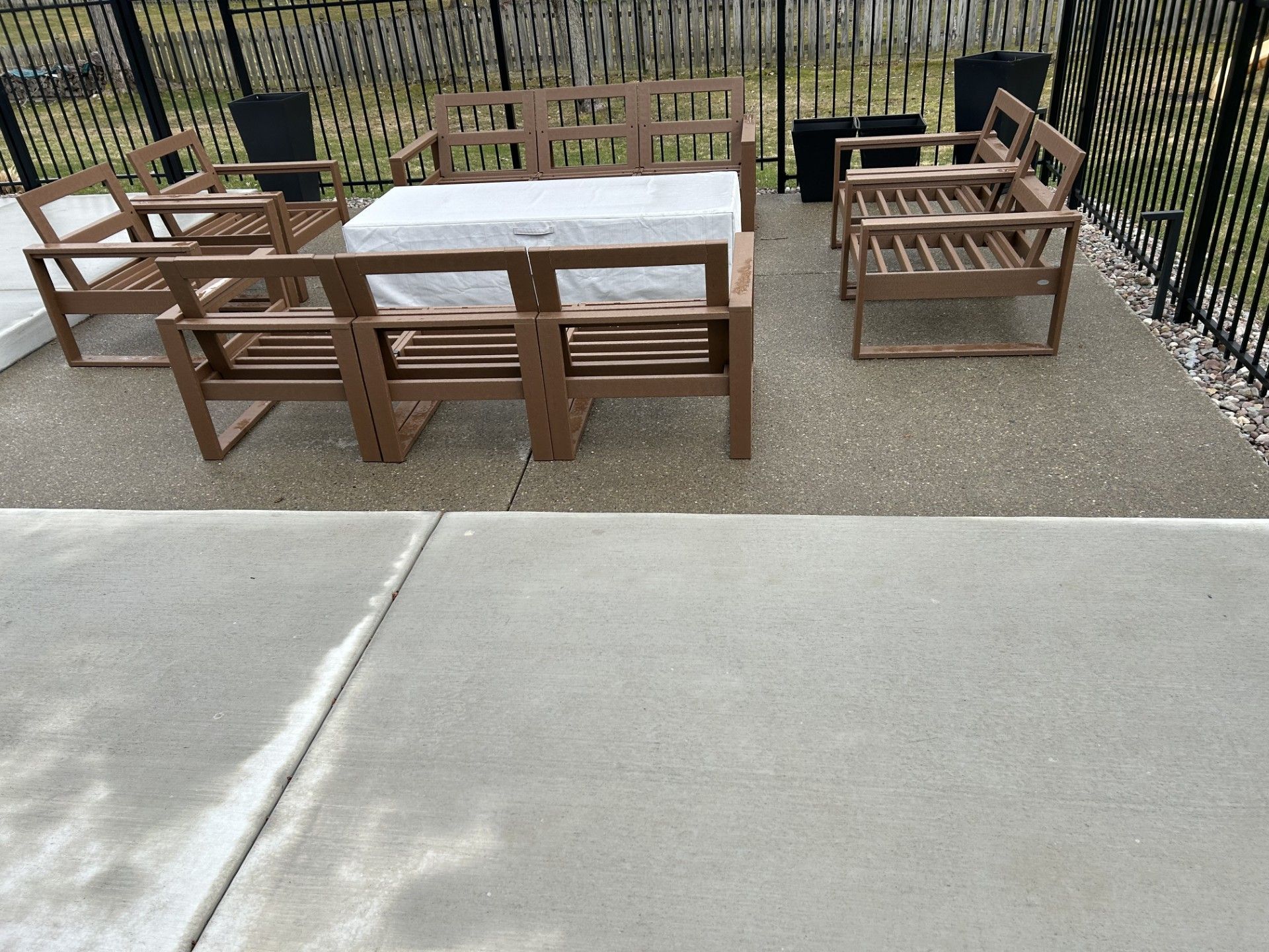 A patio with a table and chairs and a fence in the background.