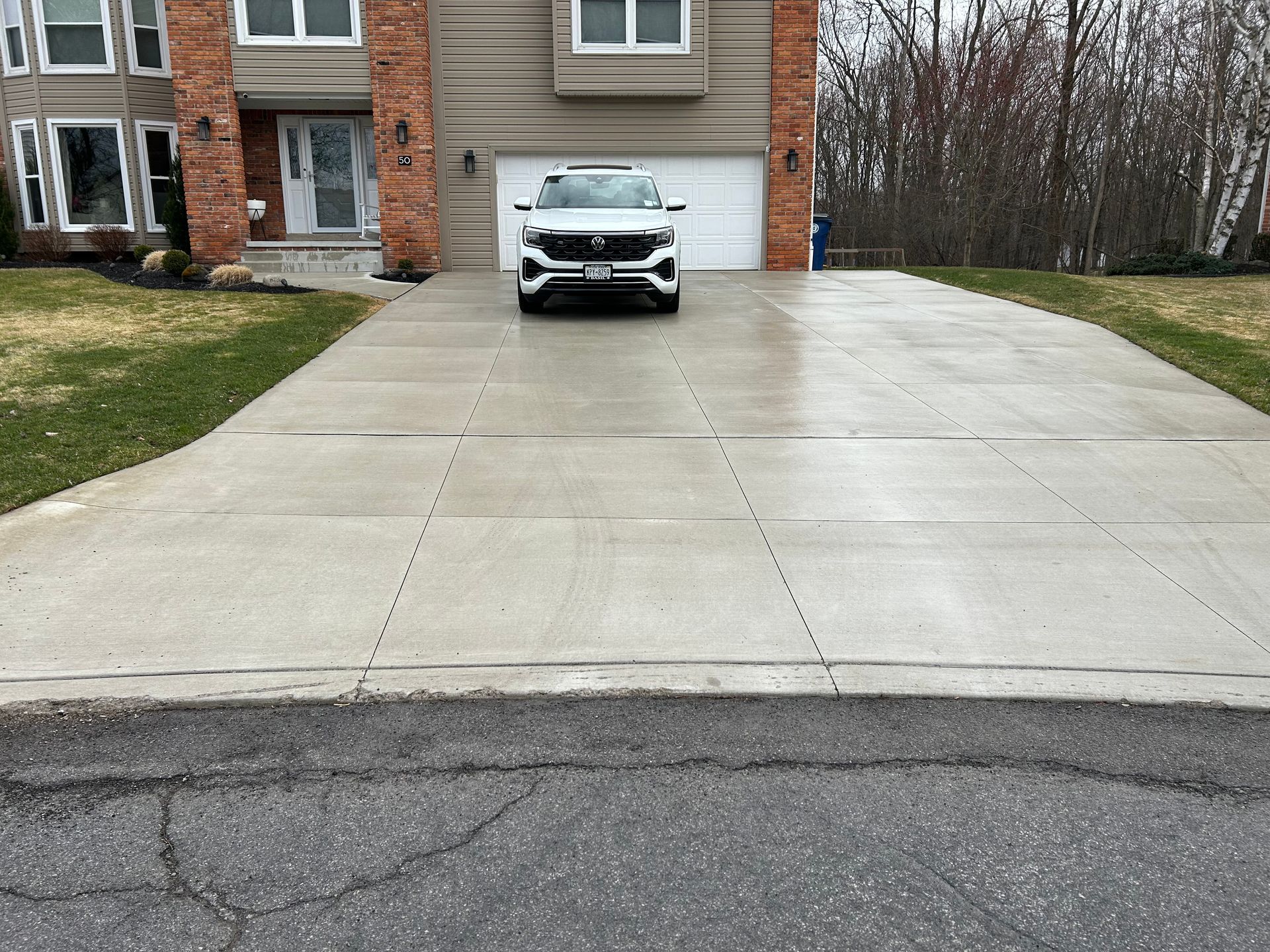A white car is parked in a driveway in front of a house.